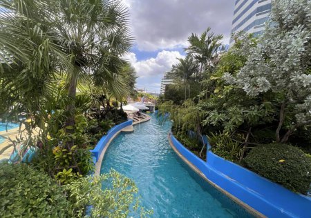 Photo for A photography of a water slide in a tropical garden with palm trees, fountain with a blue water slide in a tropical garden area. - Royalty Free Image