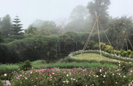 Photo for A photography of a garden with a circular bed of flowers, maypolen in a garden with a teepee and flowers. - Royalty Free Image