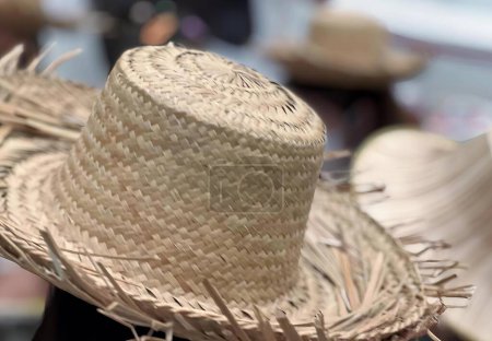 Téléchargez les photos : Une photographie d'un chapeau de paille avec une bande noire autour du bord, chapeau sombrero avec de la paille sur le dessus dans un marché. - en image libre de droit