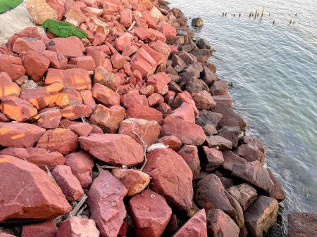 une photographie d'un grand tas de roches à côté de l'eau.