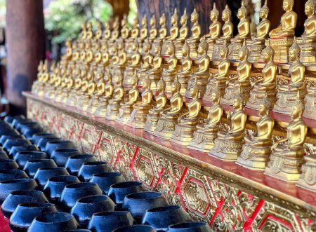 a photography of a wall of gold buddhas and blue vases.