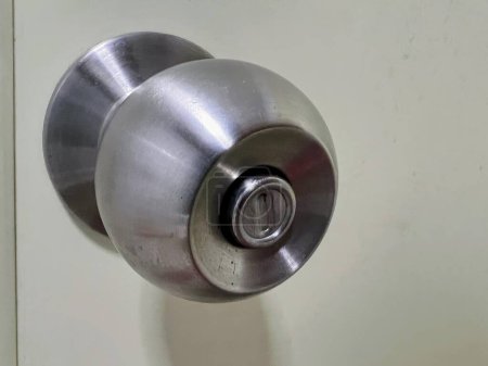 une photographie d'un bouton de porte avec une poignée métallique.