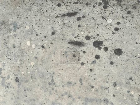 a photography of a dirty concrete floor with a black and white spot.