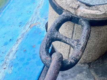 una fotografía de una cadena y un bote de basura en una acera.