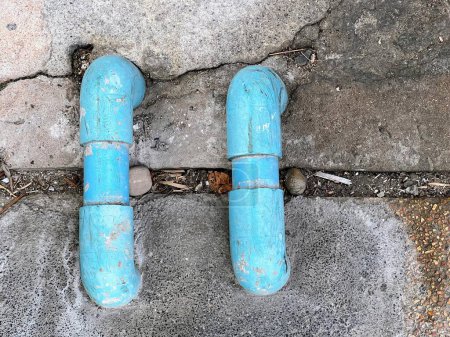 une photographie d'une paire de pipes bleues sur un trottoir.