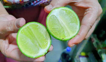 a photography of a person holding two limes in their hands.