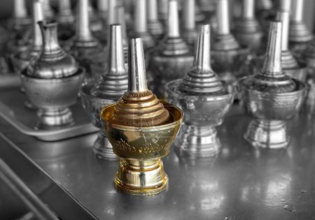 a photography of a golden cup on a table with many other silver cups.