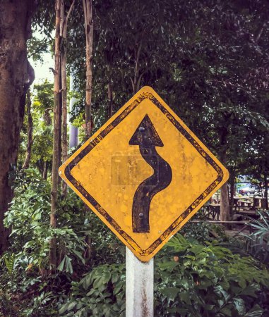 a photography of a yellow sign with a curved road sign on it.