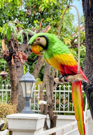 a photography of a parrot perched on a tree branch with a lamp post in the background.