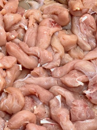 una fotografía de un montón de pollo crudo sentado en la parte superior de un mostrador.
