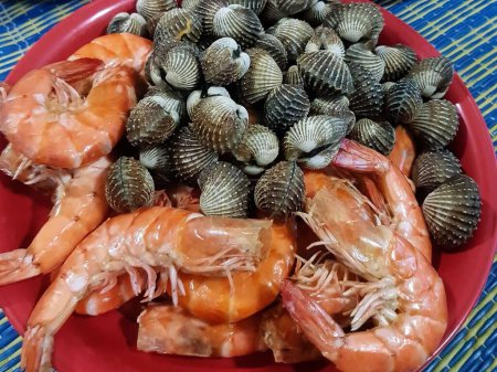 une photographie d'une assiette de crevettes, palourdes et crevettes.