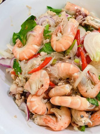 une photographie d'une assiette de crevettes et légumes avec une fourchette.