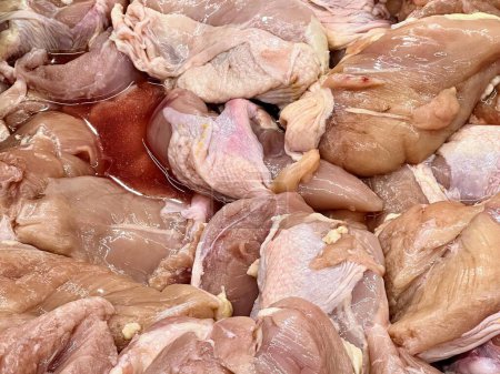 eine Fotografie eines Haufens roher Hühner, die auf einer Theke sitzen.