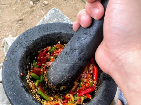 una fotografía de una persona usando un mortero para mezclar verduras.