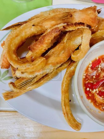 una fotografía de un plato de comida con aros de cebolla y un tazón de salsa de inmersión.
