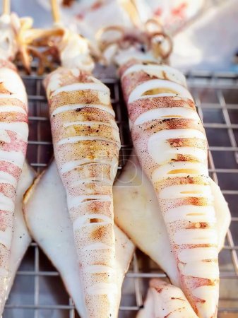 a photography of squids are cooked on a grill with a lot of sauce.