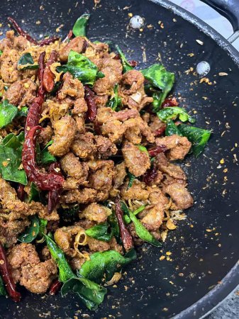 una fotografía de un wok lleno de carne y verduras en una estufa.
