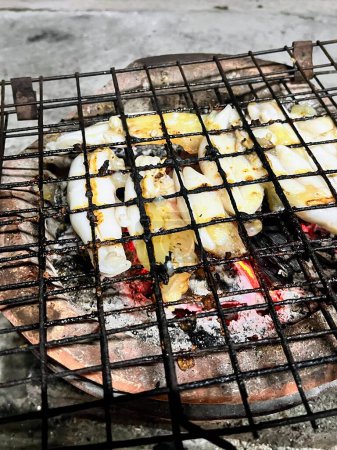 a photography of a grill with fish and vegetables cooking on it.