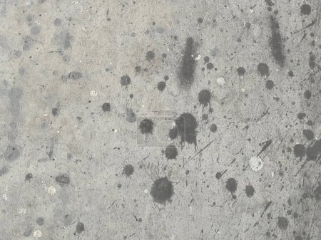 a photography of a dirty concrete surface with black spots.