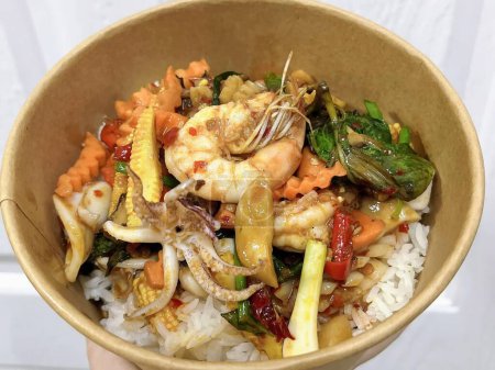 une photographie d'un bol de nourriture avec des crevettes, des légumes et du riz.
