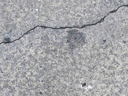 une photographie d'une fissure dans le béton montre une fissure dans le sol.