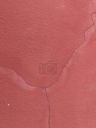 une photographie d'un mur rouge avec une fissure au milieu.