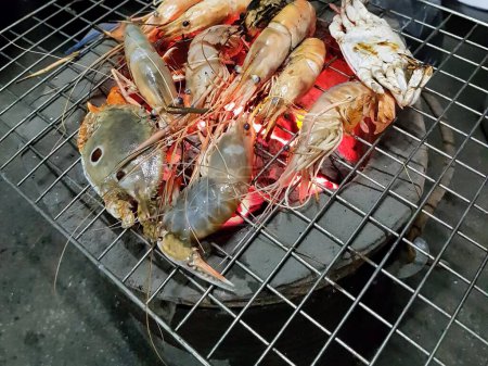 a photography of a grill with shrimps and other seafood cooking on it.