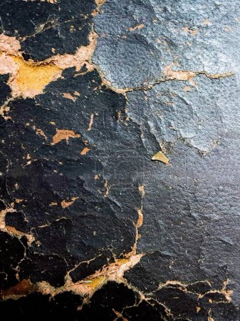 a photography of a black and yellow paint peeling on a wall.