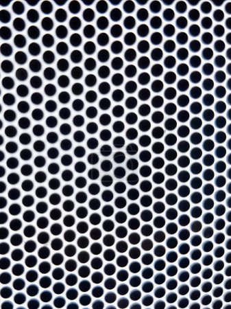 a photography of a metal grill with holes in it.