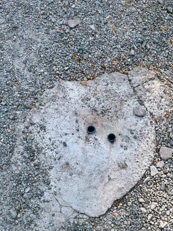 Foto de Una fotografía de una cara hecha de cemento sobre una superficie de grava. - Imagen libre de derechos