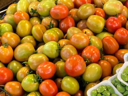 una fotografía de una pila de tomates y guisantes en una canasta.