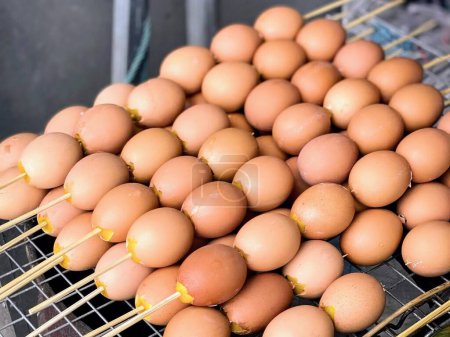 a photography of a bunch of eggs on a stick on a grill.