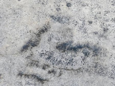 a photography of a dirty concrete surface with a black and white pattern.