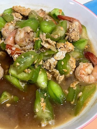 a photography of a bowl of soup with shrimp and asparagus.