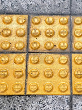 eine Fotografie eines Bürgersteigs aus gelben Ziegelsteinen mit vielen gelben Punkten.