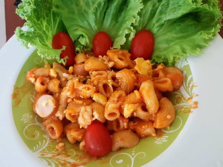 a photography of a plate of pasta with tomatoes and lettuce.