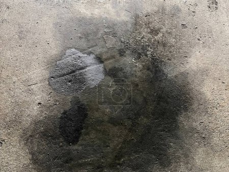 a photography of a dirty wall with a black spot on it.