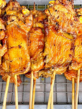 a photography of a grill with chicken and other meats on skewers.