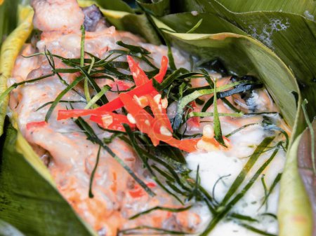 eine Fotografie eines Fischgerichts mit einer roten Blume an der Spitze.