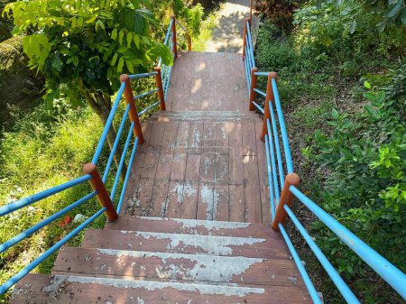 Photo for A photography of a wooden stairway going up a hill with a blue railing. - Royalty Free Image