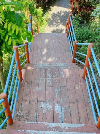 una fotografía de una escalera de madera que conduce a un exuberante parque verde.