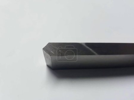 a photography of a black metal object on a white surface.