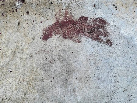 una fotografía de una superficie de hormigón sucio con una mancha roja.