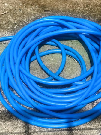 une photographie d'un tuyau bleu posé sur un trottoir.