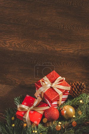 Téléchargez les photos : Joyeux Noël ! Boîte avec un cadeau, boules de Noël et branches de sapin sur un fond en bois - en image libre de droit