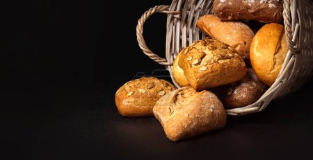 Téléchargez les photos : Basket with appetizing rolls on a black background - en image libre de droit