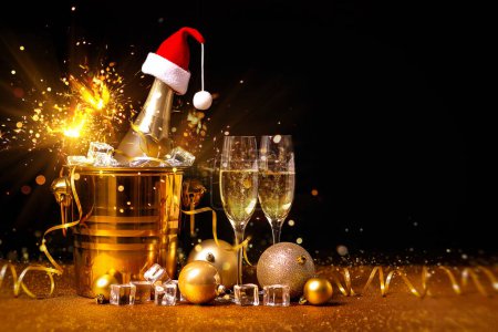 Photo for A bottle of champagne in a golden bucket with ice and two glasses of champagne on a black background in Christmas decorations. - Royalty Free Image