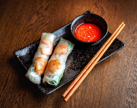 Cuisine asiatique. Rouleaux de crevettes enveloppés dans du papier de riz transparent et de la sauce piquante rouge