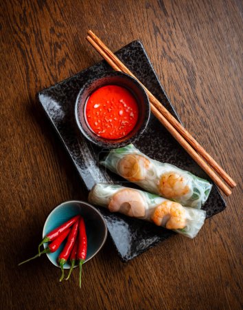 Asian cuisine. Shrimp rolls wrapped in transparent rice paper and red hot sauce