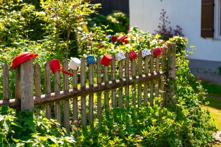 Colorful metal mugs hang on an old wooden fence in a Bavarian village